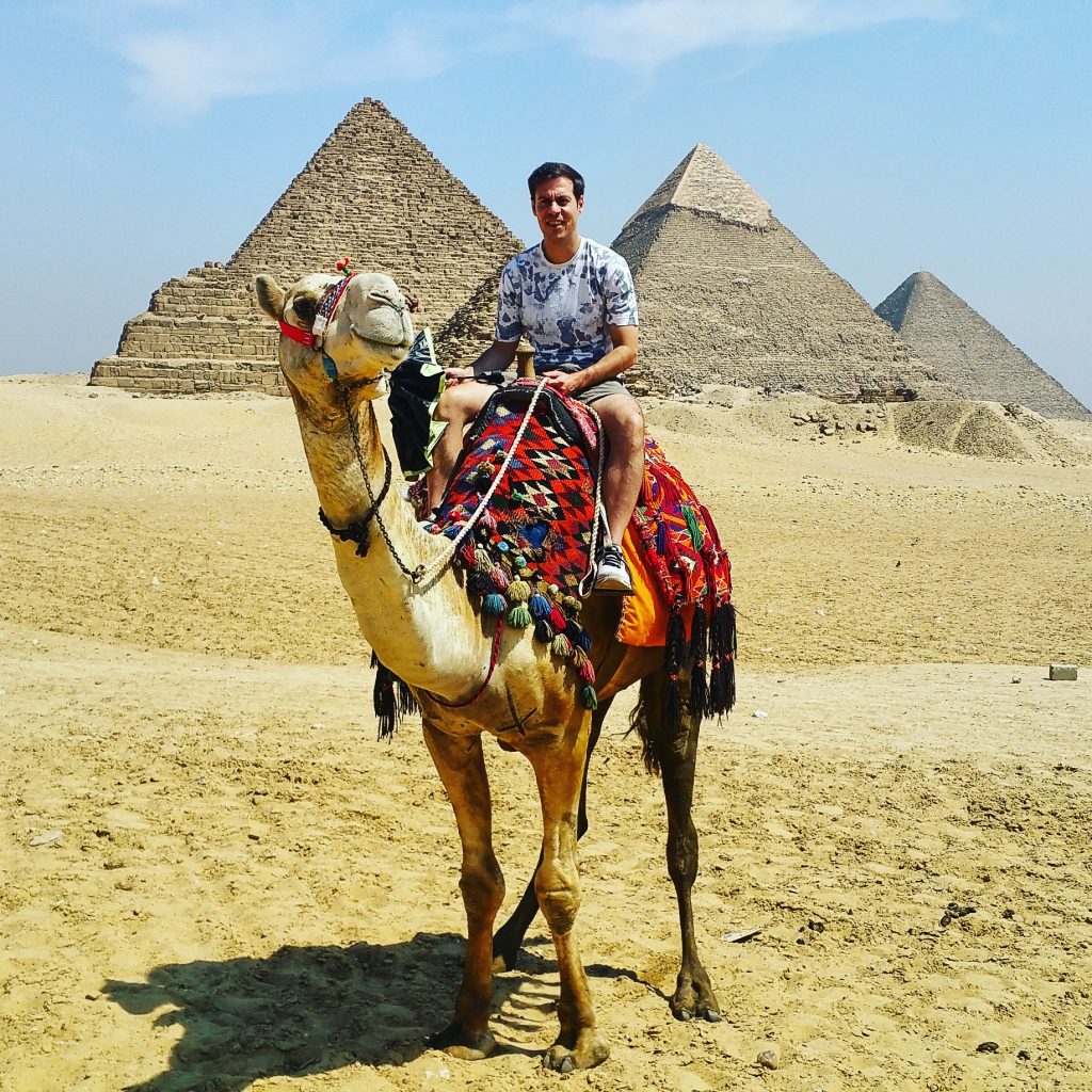 in groppa al cammello in egitto con dietro le piramidi